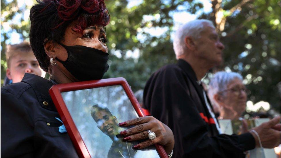 A woman crying holds a photo of a loved one