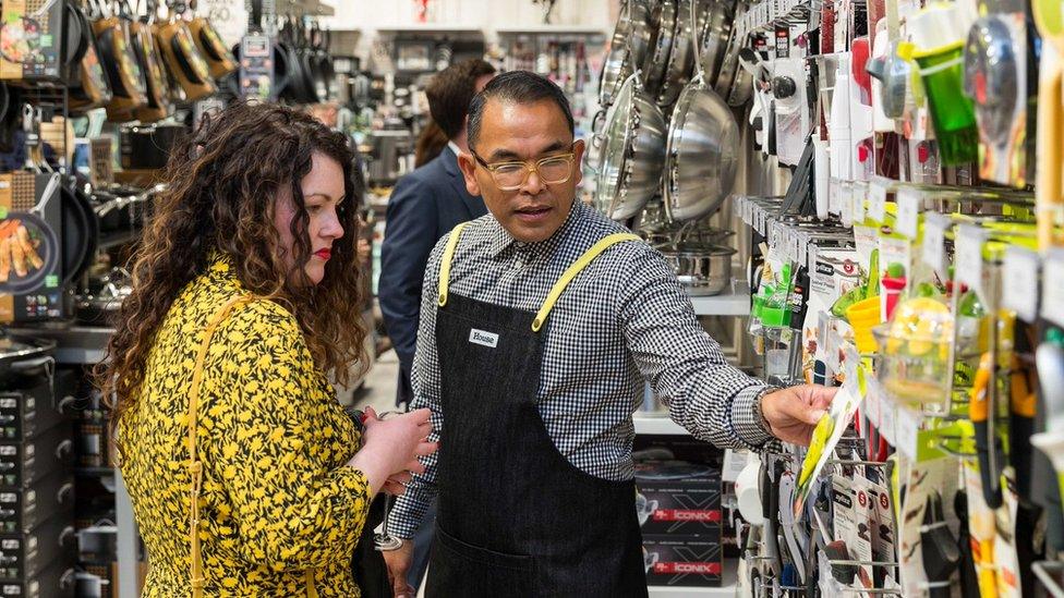 A retail assistant helps a female customer with a purchase