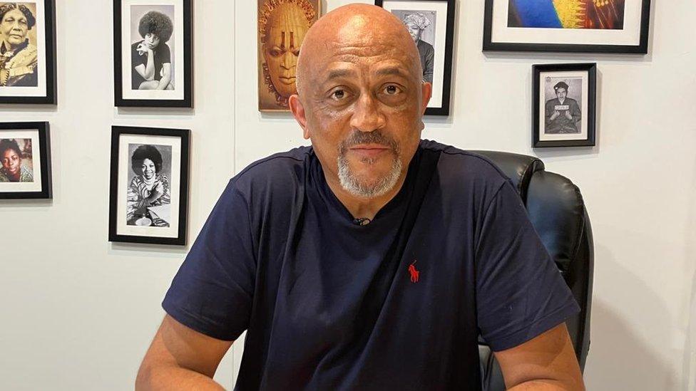 Desmond Brown sits with framed photos behind him