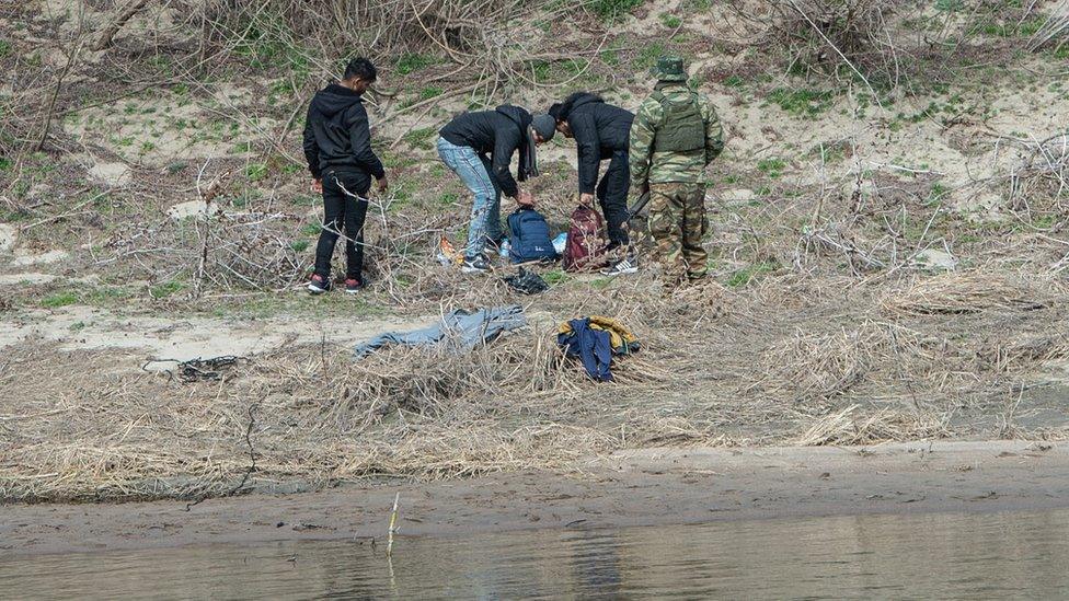 Greek border guards detain refugees and migrants on the Greek shoreline of the Evros river after they crossed from Turkey to Greece on March 04, 2020 in Edirne