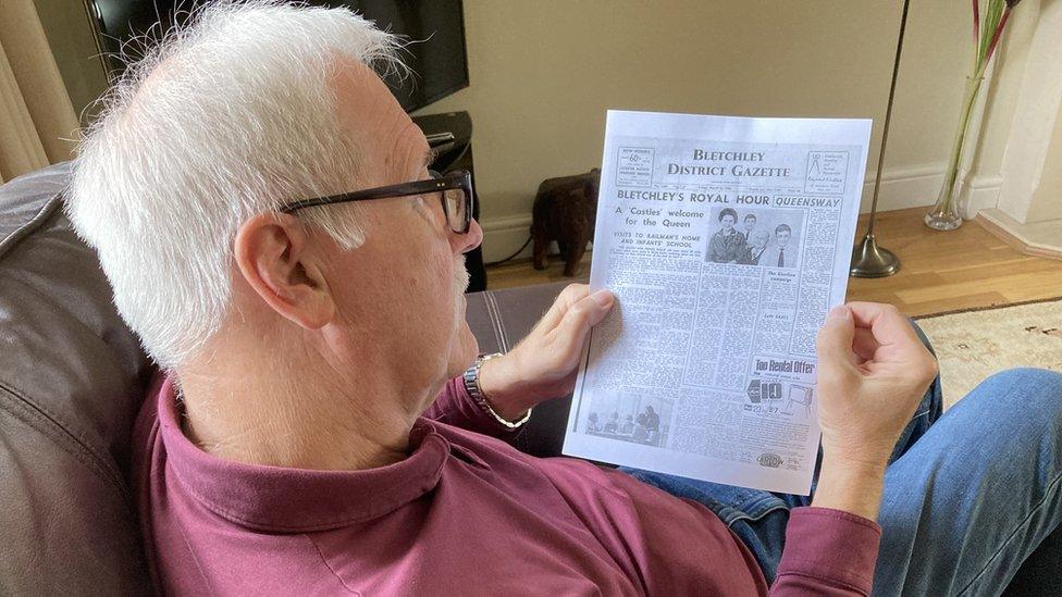 Colin Spence reading an old newspaper article of the time the Queen came to his former home in Bletchley