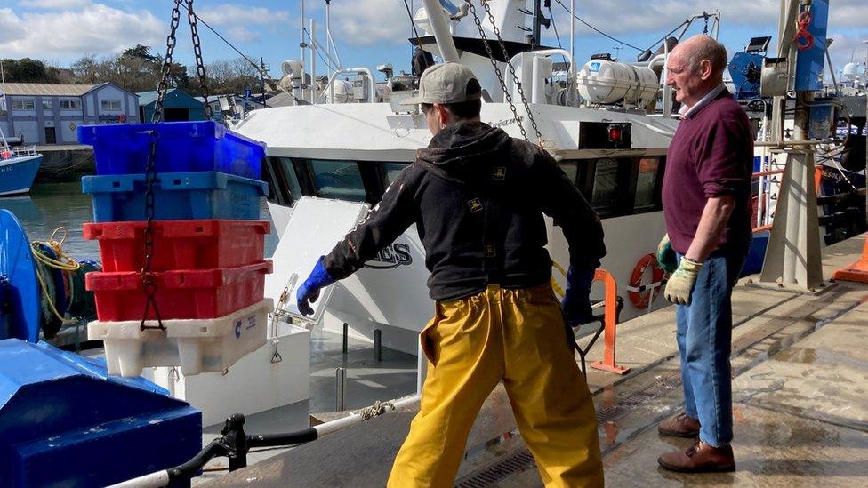 Fishermen stand at the harbour