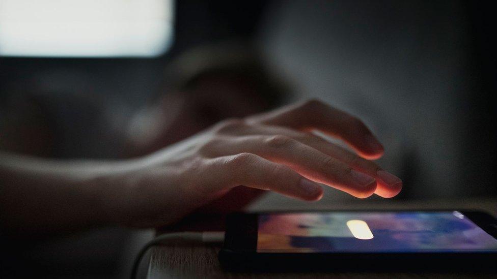 Man checking phone on bedside