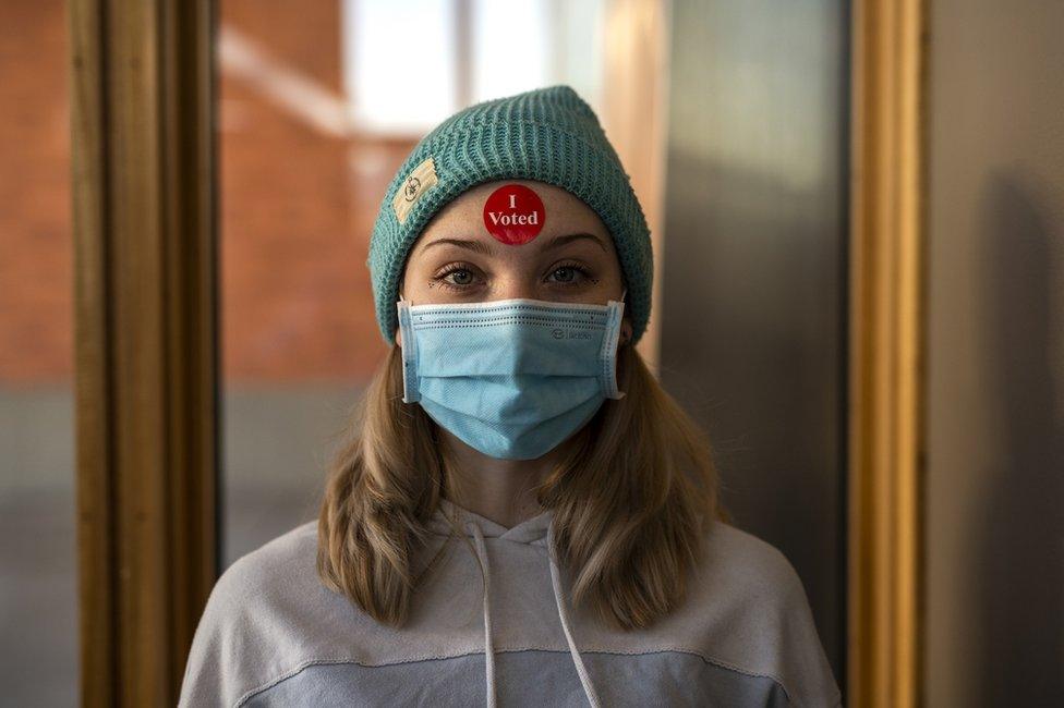 A voter poses for a portrait while wearing an "I Voted" sticker on her forehead