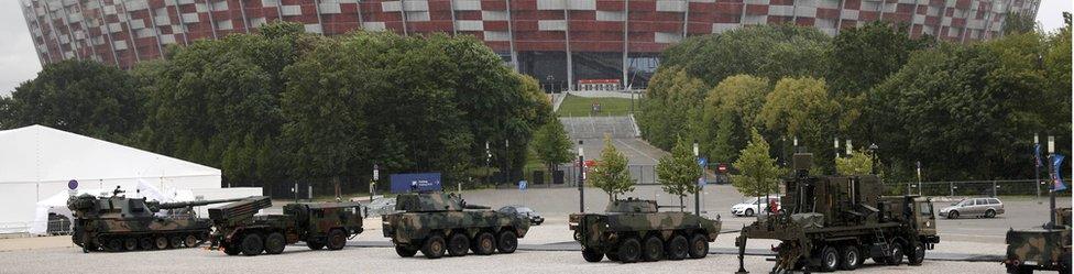 Armoured military vehicles are parked outside PGE National Stadium in Warsaw (8 July)