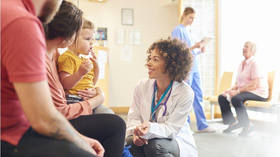 A doctor talks to a child in a waiting room