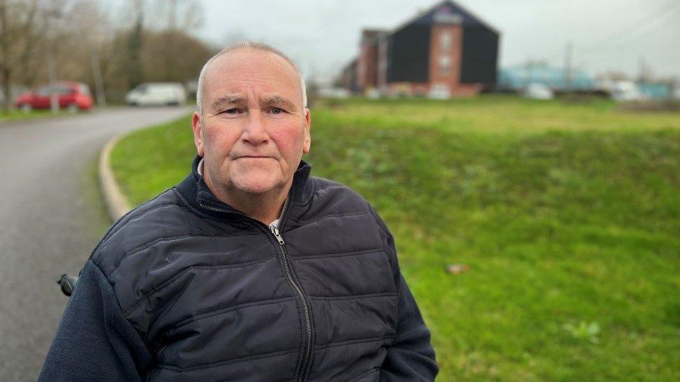 Peter Shanks with the hotel on an industrial estate in he background.