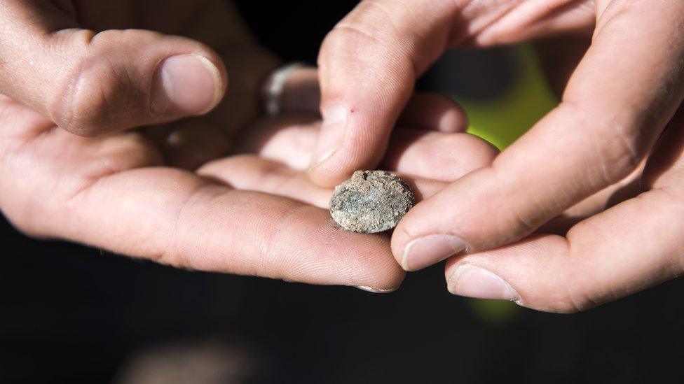 A Waterloo Uncovered team member shows off an artillery shell