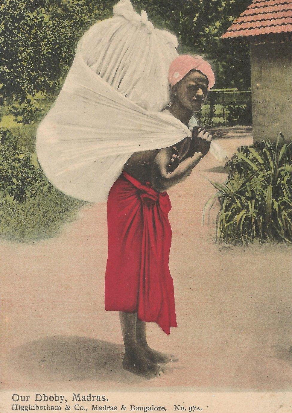 A picture postcard of a dhoby or washerman carrying a large cloth bag on his back