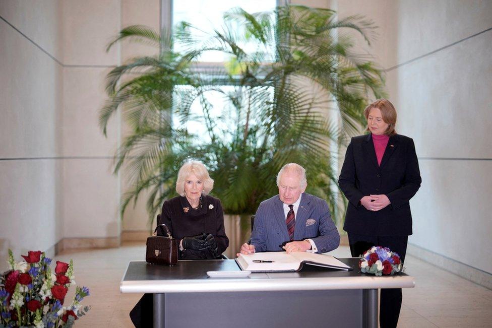 Britain's King Charles, accompanied by Camilla, the Queen Consort, signs a guest book at the Bundestag