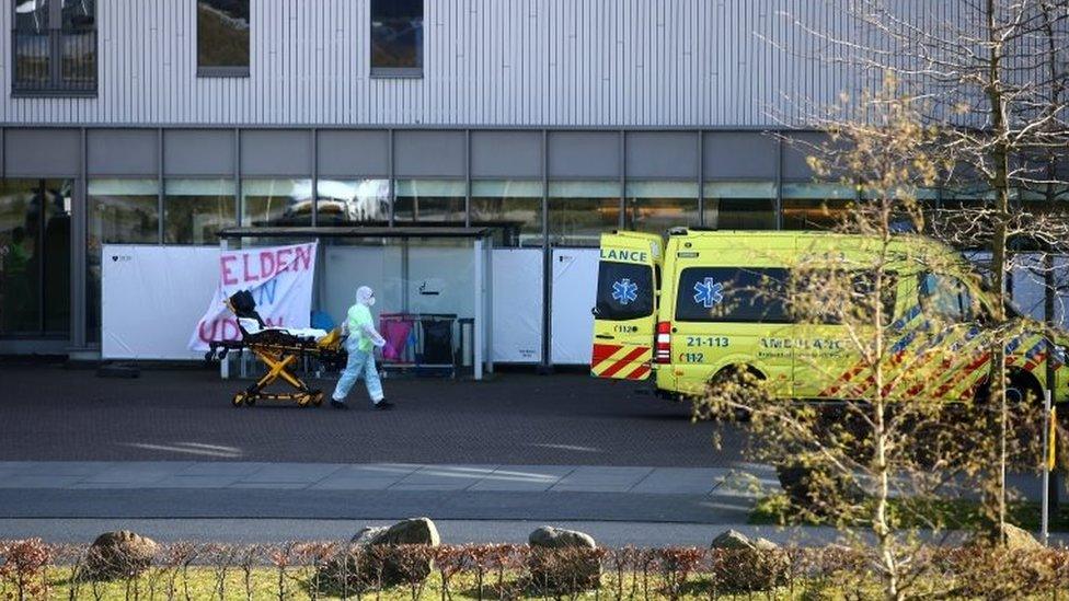 A man in protective gear wheels a stretcher into a hospital in Uden, the Netherlands