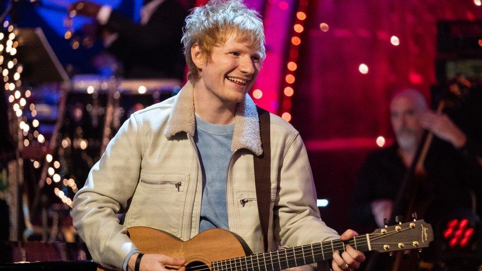 Ed Sheeran smiling by his guitar