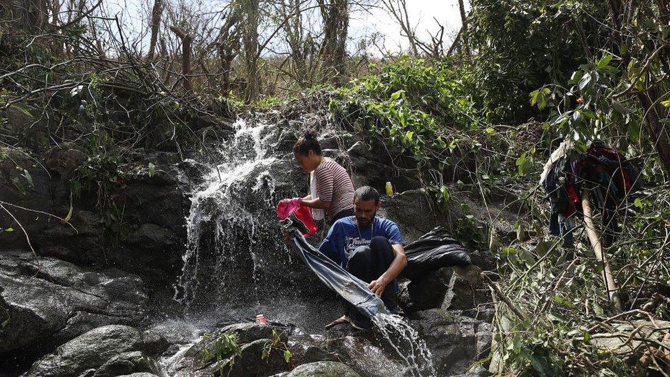 A couple washes their clothing in a stream on Sunday