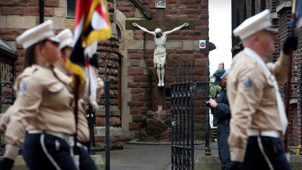 Bandsmen march past a Catholic church during a parade