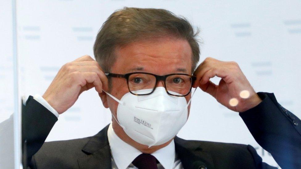 Austrian Health Minister Rudolf Anschober adjusts his face mask during a news conference in Vienna, 13 April