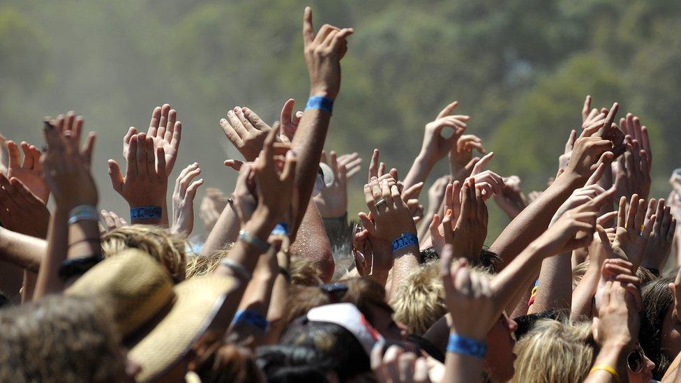 People hold their wristbands up at a festival