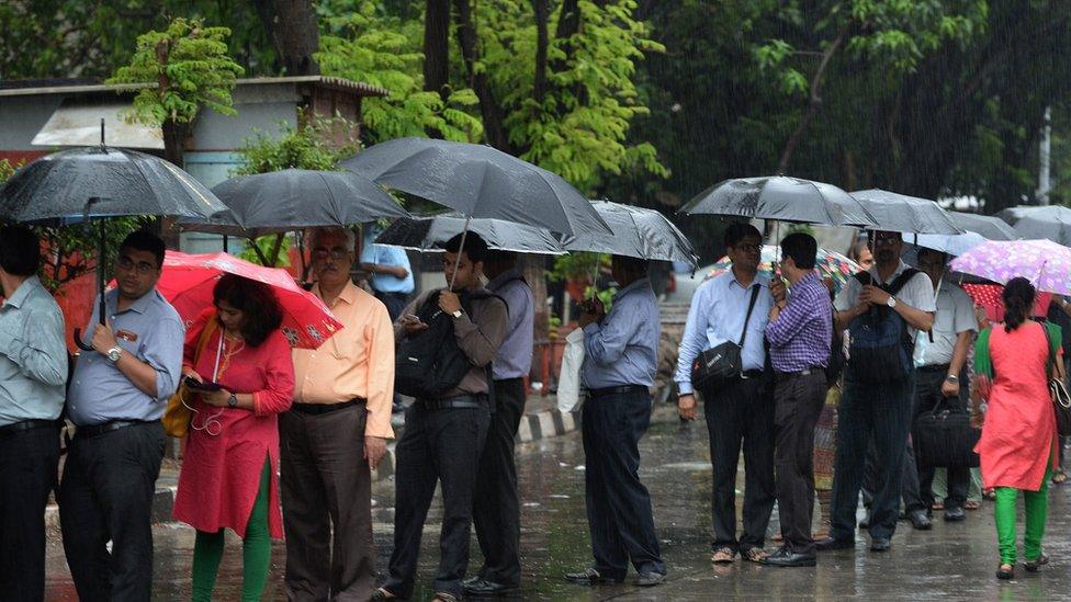 Indian commuters queue in rain as they wait for taxi at a business district in Mumbai on July 23, 2015