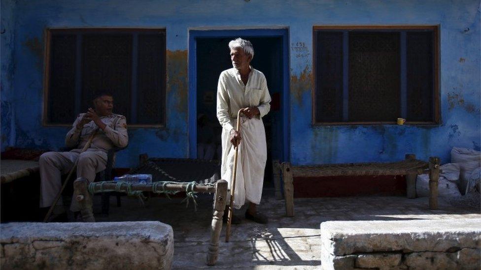 A policeman sits near a relative of Akhalaq Saifi, who was killed by a mob, outside Saifi"s house at Bisara village in Uttar Pradesh, India, October 2, 2015.