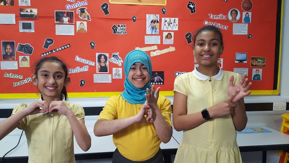 Children spell out the letters BSL in sign language.