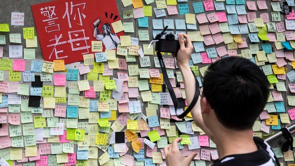 A man taking photographs of artwork and messages in support of protesters opposed to a China extradition law