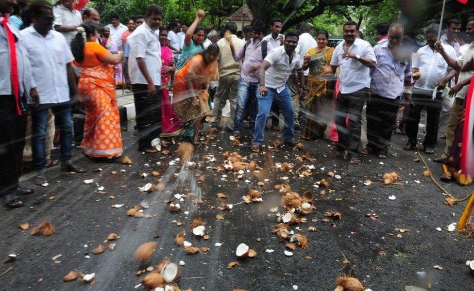 Members of the All India Anna Dravida Munnetra Kazhagam (AIADMK) break coconuts as they celebrate victory at the party office in Chennai on May 19, 2016.