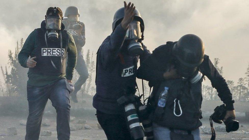 Photojournalists and video journalists wearing gas masks flee from teargas during clashes with Israeli forces near an Israeli checkpoint in the West Bank city of Ramallah.