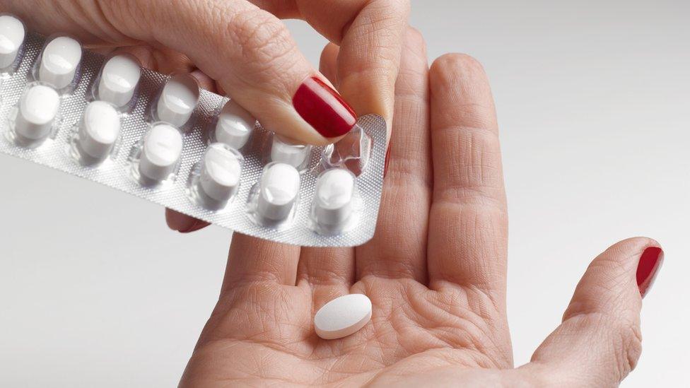 A woman with a strip of tablets