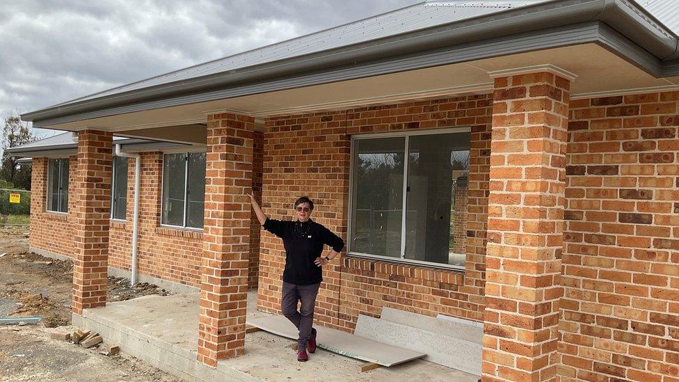 Elizabeth Atkin standing in front of her partially rebuilt house