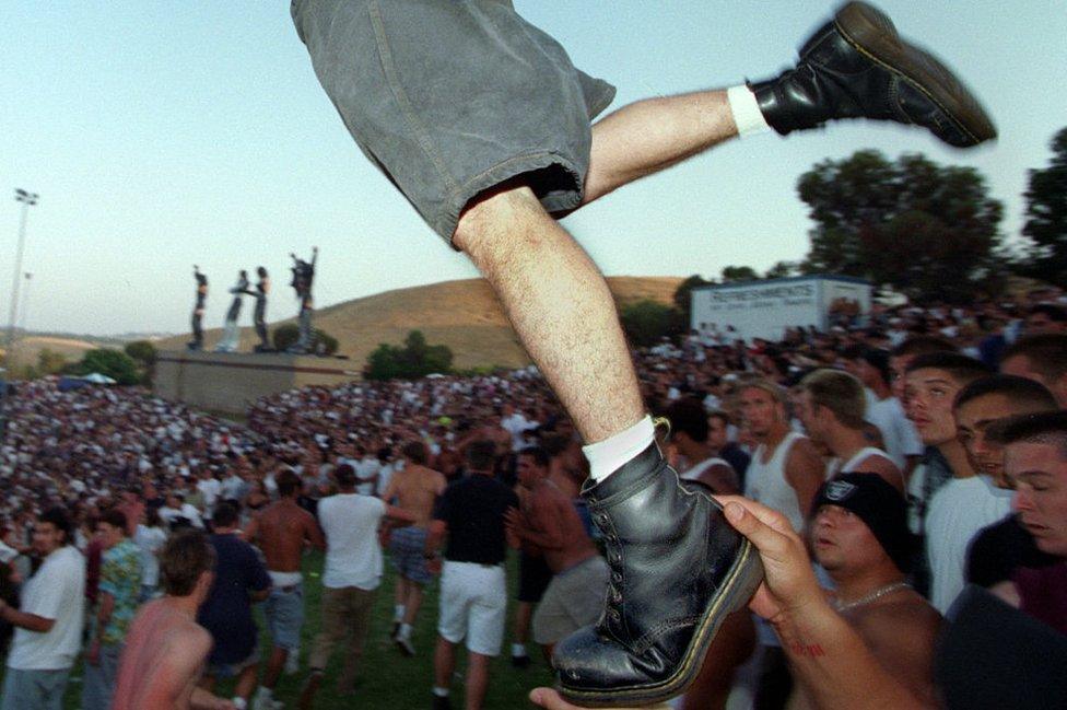 A mosher wearing Doc Martens takes flight into the moshpit as he is boosted by a friend during the KORN performance at the KROQ Weenie Roast at Irvine Meadows Saturday afternoon. shot 6/15/96