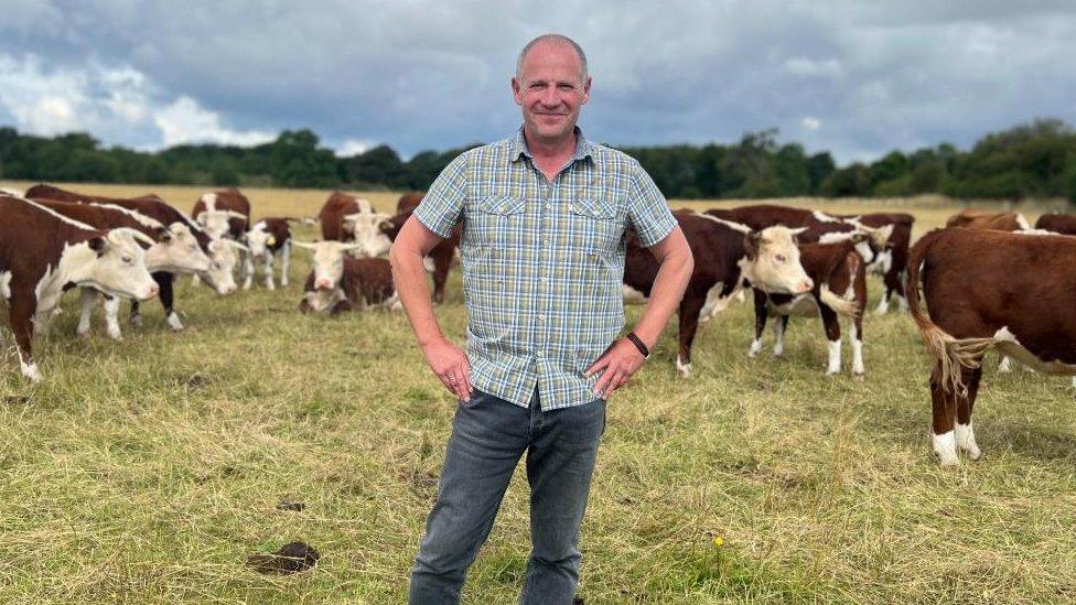 Jonty Brunyee standing in front of a herd of cows