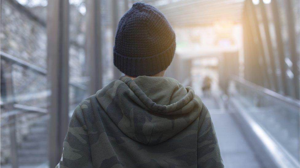 A stock image of teenage boy wearing a hoodie and a hat