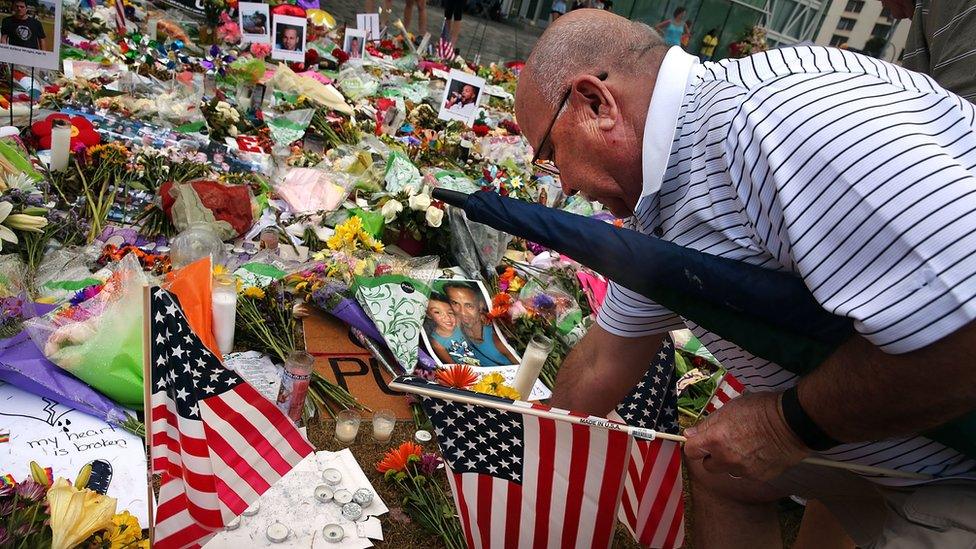 A man places American flags at a memorial down the road from the Pulse nightclub in Orlando on June 19