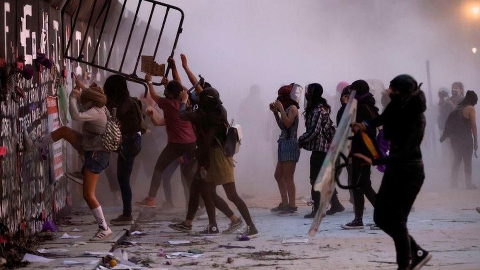 People try to take down the fences placed outside the National Palace