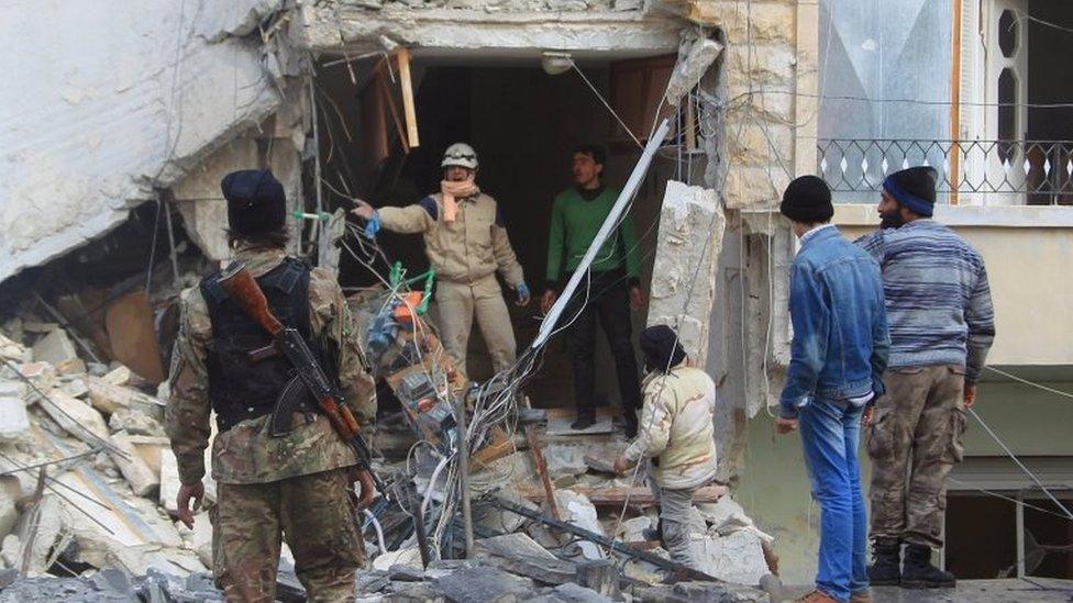 A civil defence member gestures towards a rebel fighter as they search for survivors