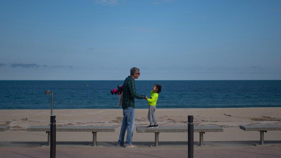 A man and his daughter walk by La Mar Bella beach on April 26, 2020 in Barcelona, Spain. Children in Spain