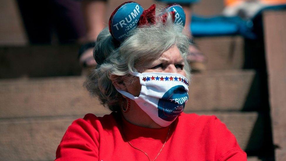 A female Trump supporter wears a face mask