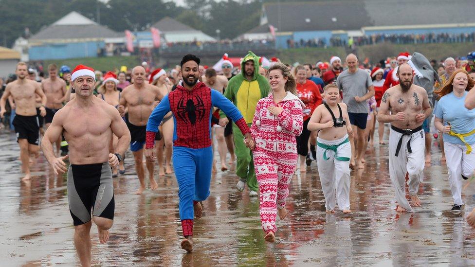 People in fancy dress running into the sea