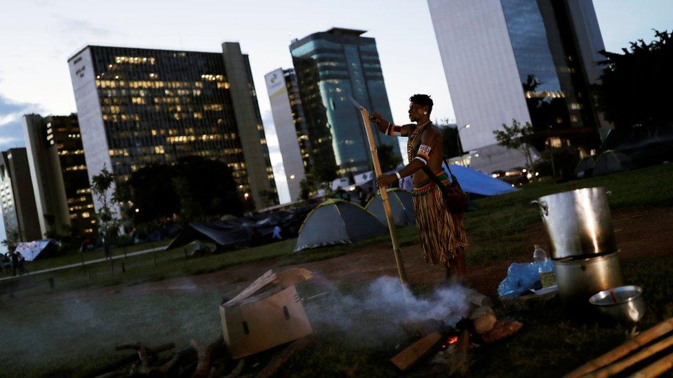 An Indigenous man prepares meal at the Free Land camp