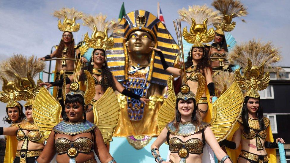 Performers in costumes standing on an ancient Egyptian style float participate