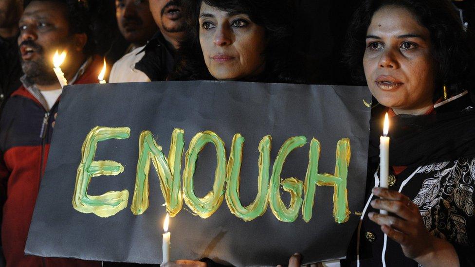 Pakistani journalists holding up sign with the word ENOUGH on it, light candles to pray for the victims who were killed in an attack at the Army run school in Peshawar, during a memorial ceremony in Islamabad Pakistan, 16 December 2014.