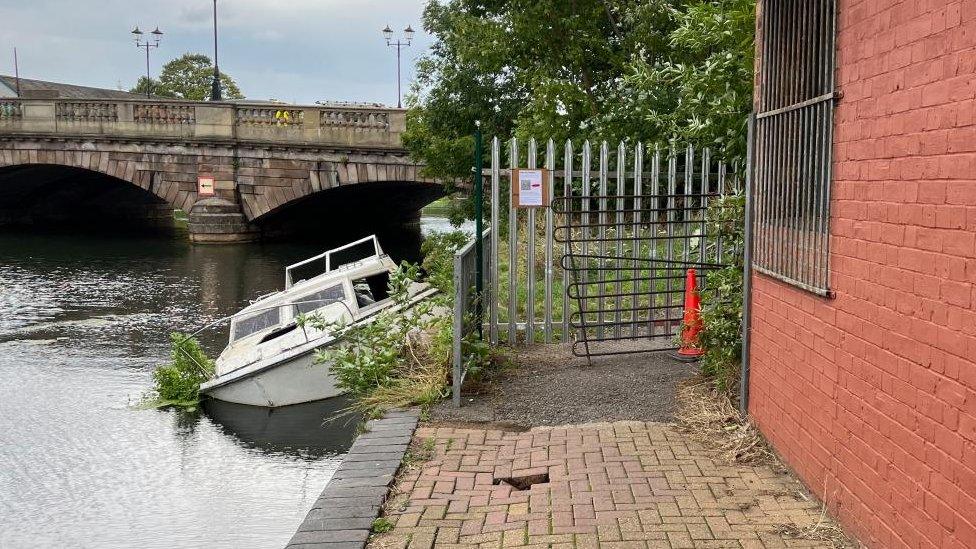 River with bridge in the background and path blocked by iron fence in the foreground