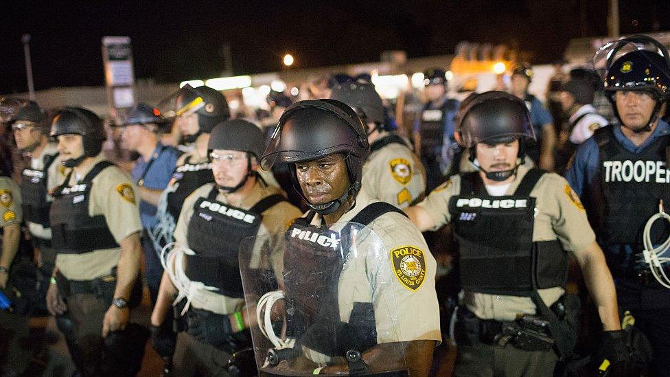 Police wearing riot gear in Ferguson, Missouri, stand in a line.