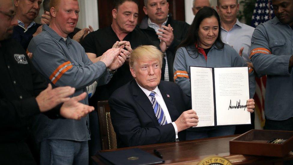 President Trump, holding up signed memo imposing tariffs on steel and aluminium