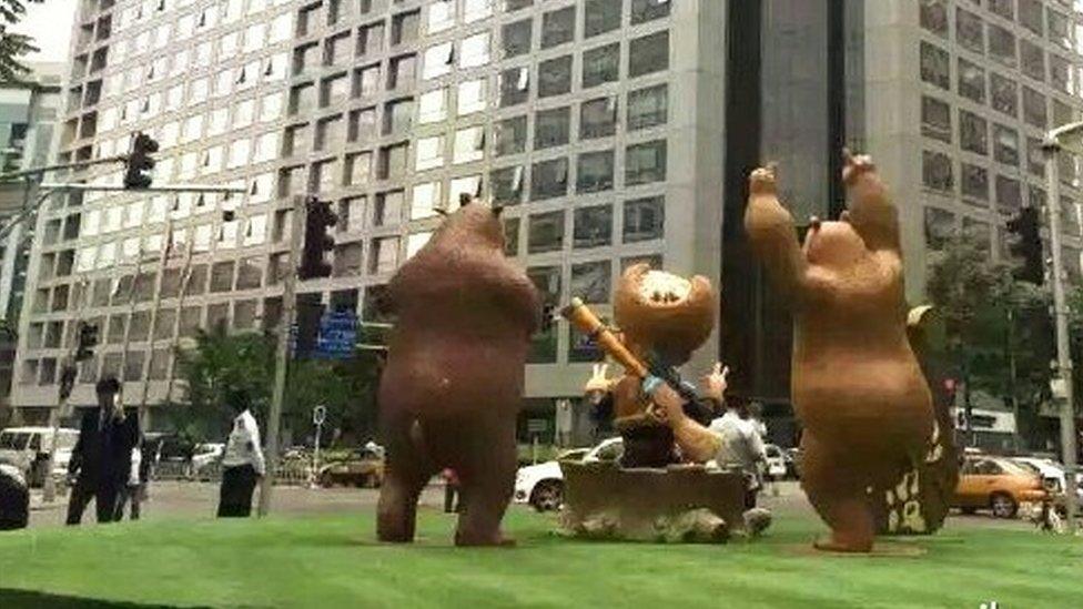 The bear statues seen from the back, with the government building in front of them