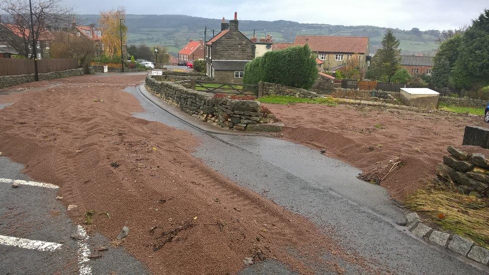 A road and part of a field covered in gravel