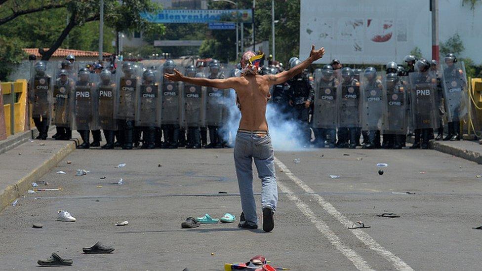 A demonstrator gestures in front of Venezuelan national policemen standing guard at the Simon Bolivar international bridge, in Cucuta, Colombia