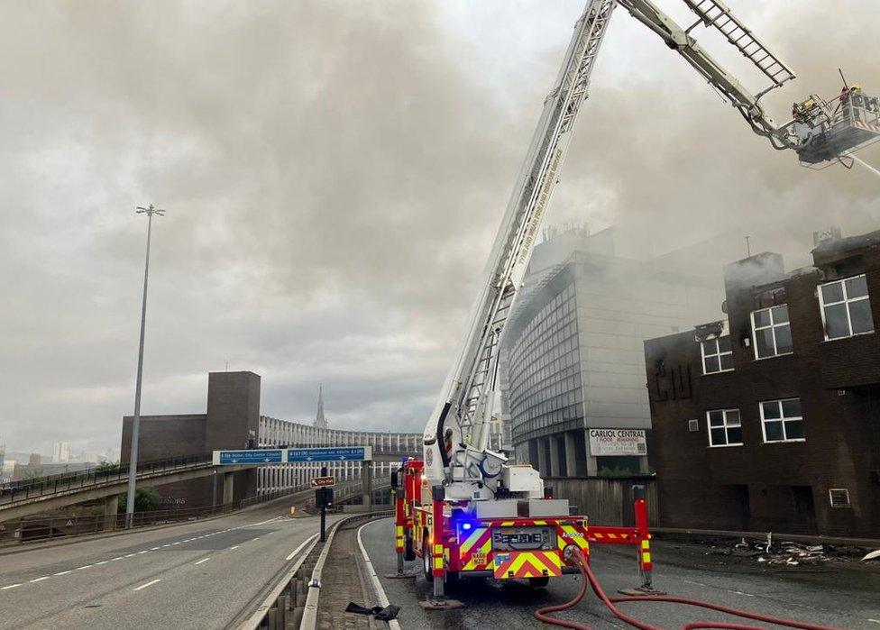 Firefighters on a crane platform extinguish the blaze at Carliol Square, next to the Central Motorway