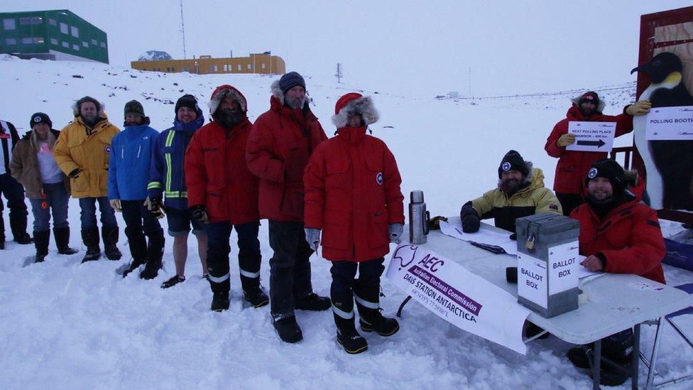 A group of people queue in the snow to vote at a ballot box outside