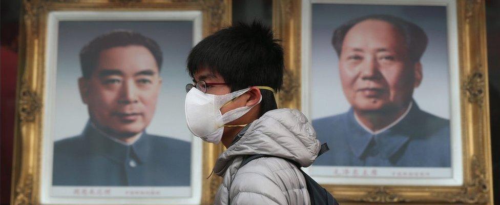 A Chinese man wearing a mask walks by portraits of former Chinese leaders Mao Zedong (R) and Zhou Enlai in a shopping street during a hazy day in Beijing city, China, 22 December 2015