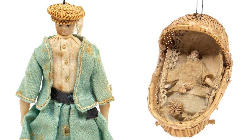 The doll inside a woven crib and wax doll missing a leg which had been owned by Queen Victoria